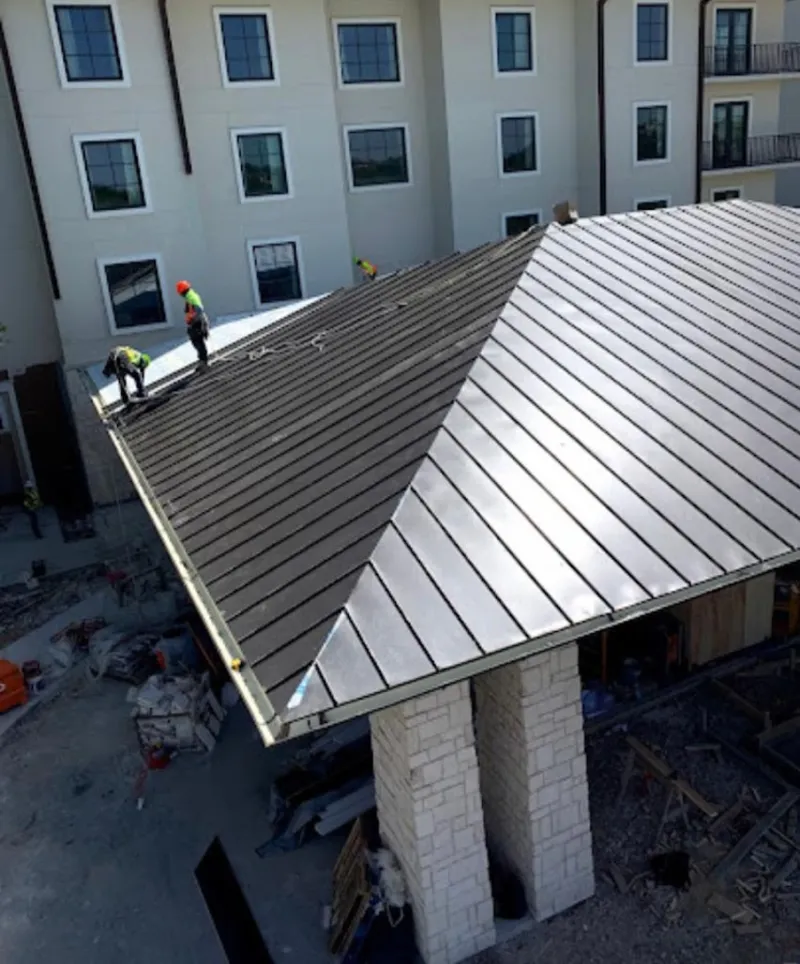 Crew installing standing seam metal roof panels on a commercial project in Bellwood